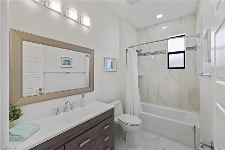 Full bath featuring shower / bathtub combination with curtain, vanity, light marble finish flooring, and recessed lighting
