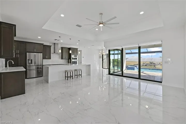 Kitchen featuring stainless steel appliances, light stone countertops, tasteful backsplash, a kitchen bar, and open floor plan