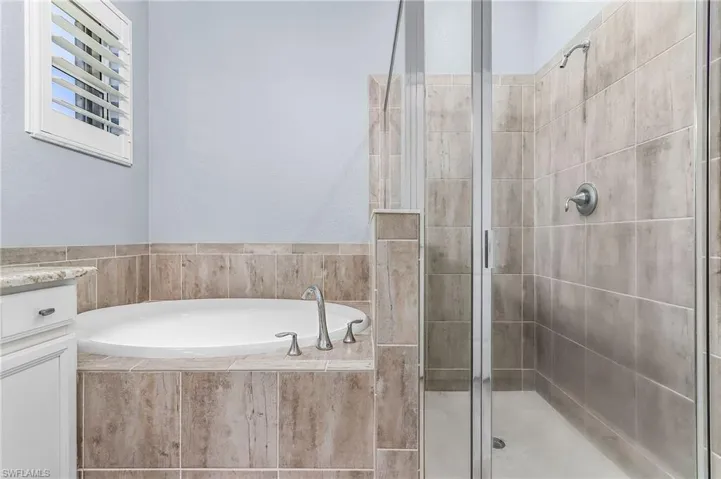 Full bathroom featuring a stall shower, a bath, and vanity