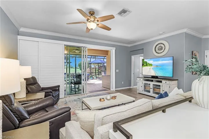 Living area with a ceiling fan, wood finished floors, and crown molding
