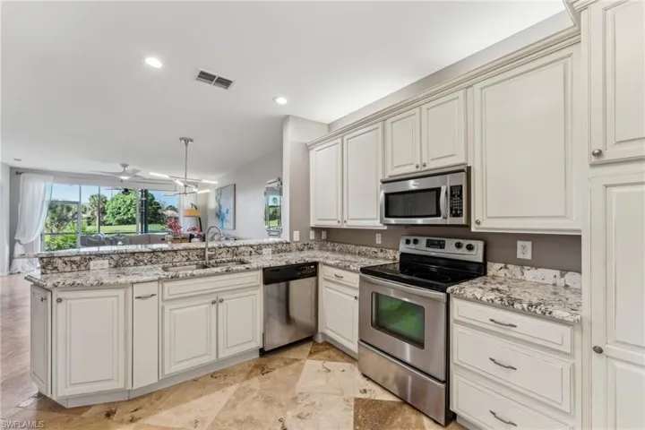 Kitchen with visible vents, appliances with stainless steel finishes, light stone counters, a peninsula, and a sink