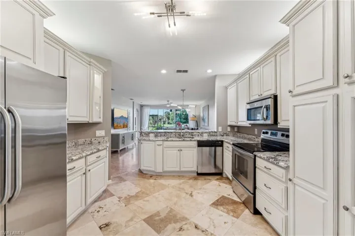 Kitchen with a peninsula, visible vents, appliances with stainless steel finishes, and white cabinets