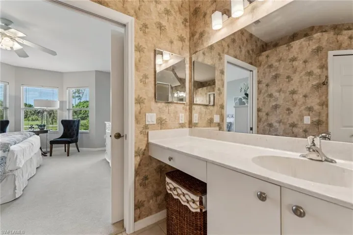 Ensuite bathroom with ceiling fan, connected bathroom, vanity, baseboards, and wallpapered walls