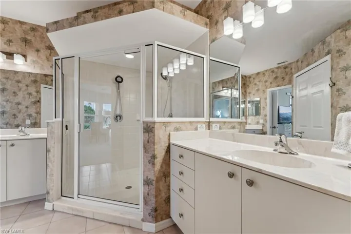 Bathroom featuring a shower stall, a sink, and wallpapered walls