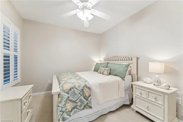 Bedroom with light carpet, ceiling fan, and baseboards