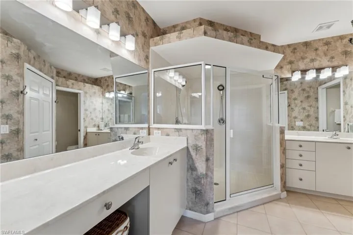 Full bath with a stall shower, tile patterned floors, vanity, and wallpapered walls