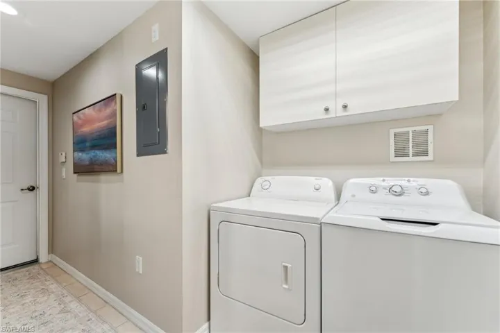 Washroom featuring visible vents, cabinet space, washing machine and dryer, electric panel, and baseboards