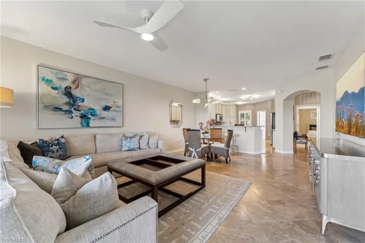 Living area featuring baseboards, visible vents, arched walkways, and a ceiling fan