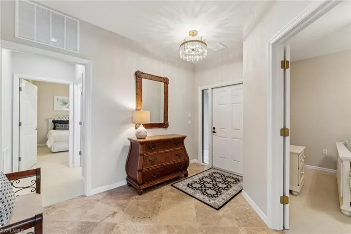 Entrance foyer with visible vents, a notable chandelier, and baseboards