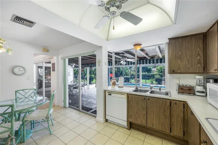 Kitchen featuring ceiling fan, sink, white appliances, and light tile floors