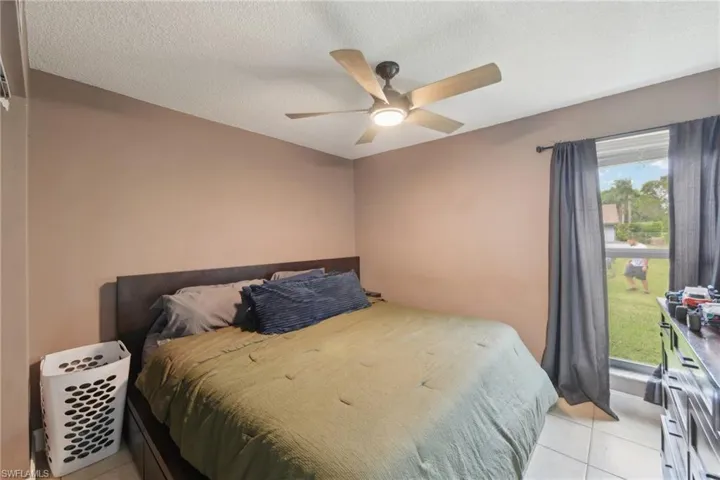 Tiled bedroom with ceiling fan and a textured ceiling