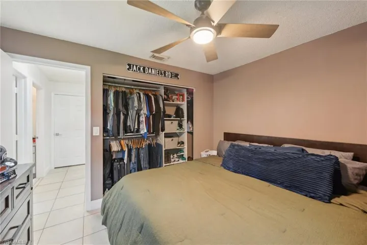 Tiled bedroom with a textured ceiling, a closet, and ceiling fan