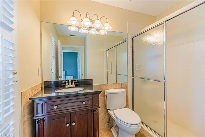 Bathroom with tile walls, walk in shower, tile floors, toilet, and vanity