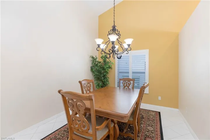 Dining area featuring lofted ceiling, light tile floors, and an inviting chandelier
