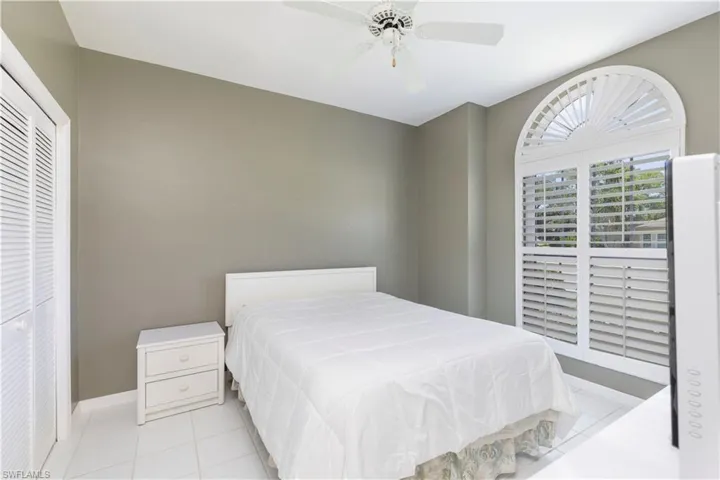 Tiled bedroom featuring ceiling fan and a closet