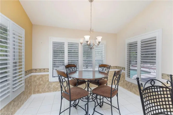 Dining room featuring a notable chandelier, lofted ceiling, and light tile flooring