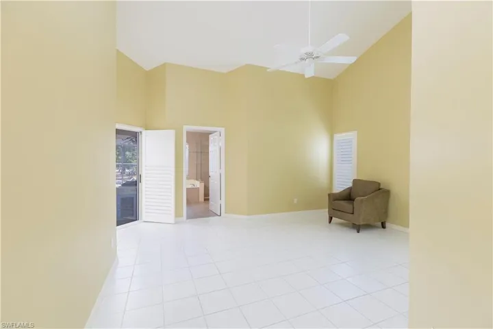 Tiled spare room with high vaulted ceiling and ceiling fan