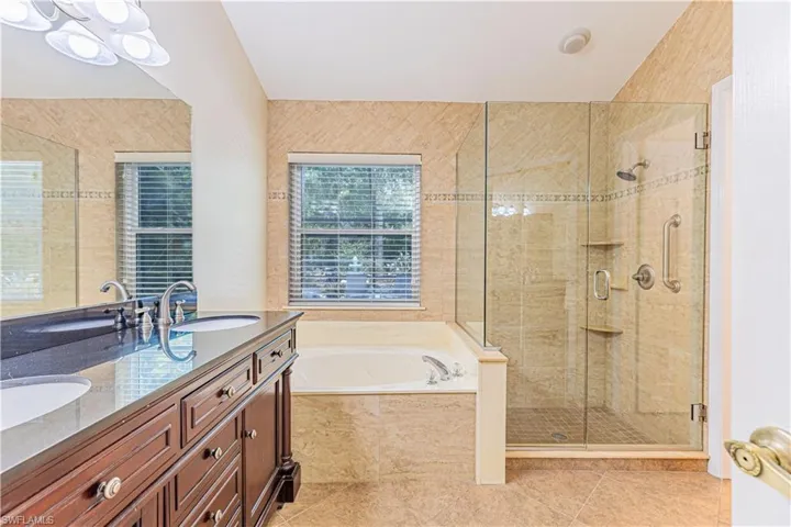 Bathroom featuring large vanity, tile flooring, dual sinks, and plus walk in shower