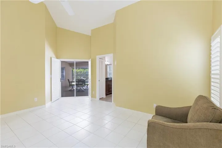 Living area with a high ceiling, ceiling fan, and light tile flooring