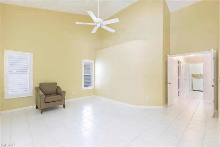 Unfurnished room featuring high vaulted ceiling, ceiling fan, and light tile floors