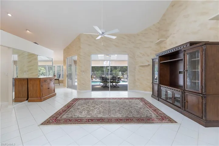 Unfurnished living room with high vaulted ceiling, ceiling fan, and light tile floors