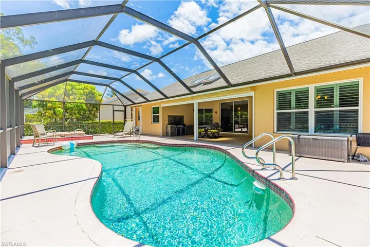 View of pool with a patio area and glass enclosure