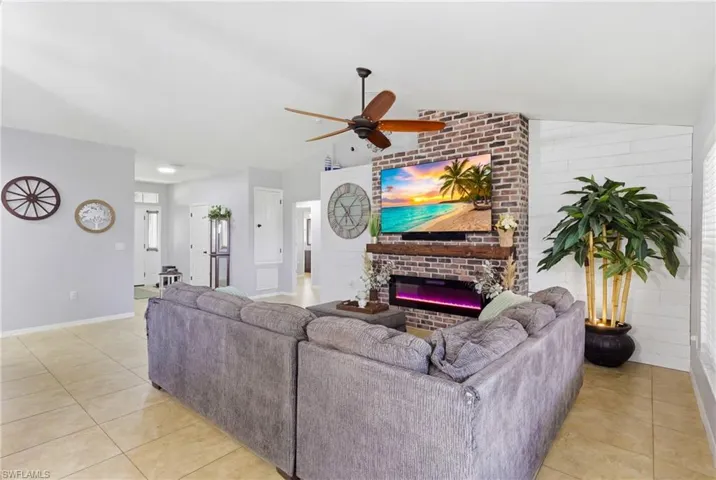 Light-filled living area featuring a striking brick accent wall and electric fireplace.