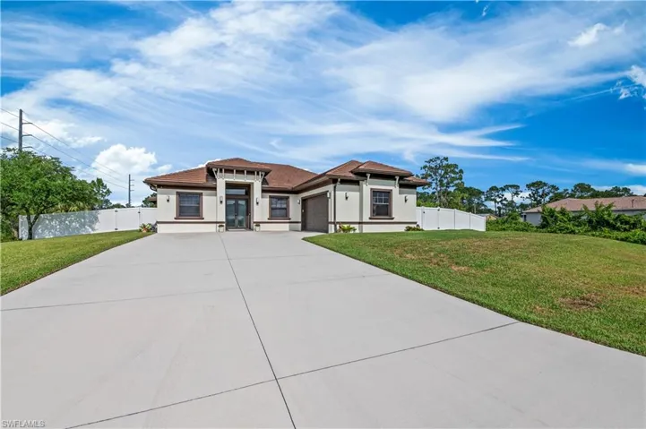 Prairie-style home with driveway, a front yard, an attached garage, and fence