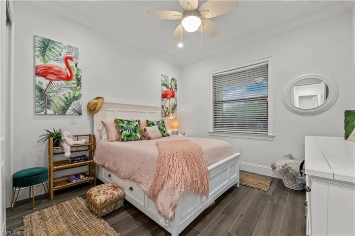 Bedroom featuring a ceiling fan, baseboards, dark wood-type flooring, and crown molding