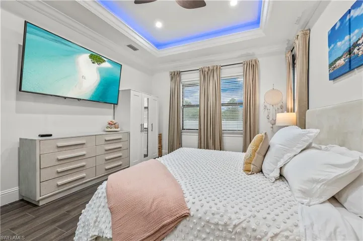 Bedroom featuring visible vents, dark wood-style flooring, a raised ceiling, and ornamental molding