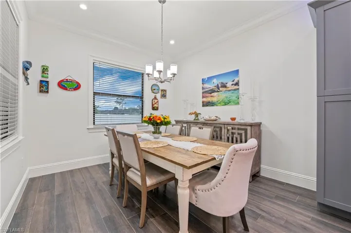 Dining room featuring dark wood finished floors, crown molding, baseboards, and a chandelier