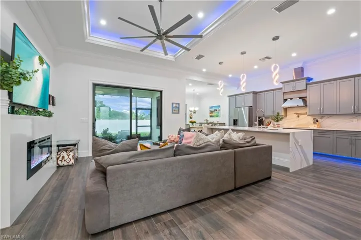 Living area featuring recessed lighting, dark wood-style floors, ornamental molding, and a ceiling fan