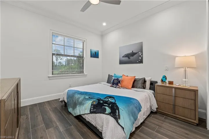 Bedroom featuring a ceiling fan, baseboards, wood tiled floor, recessed lighting, and crown molding