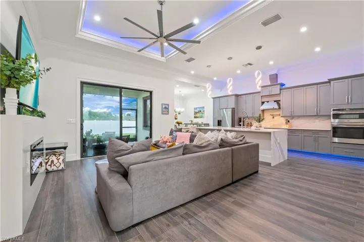 Living room with visible vents, crown molding, a ceiling fan, and dark wood-style flooring