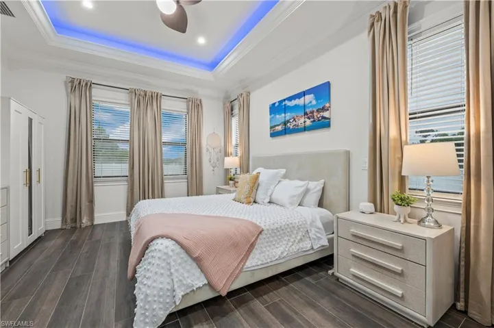 Bedroom with ornamental molding, a tray ceiling, and wood tiled floor