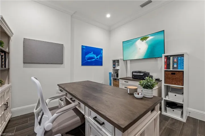 Office space featuring dark wood-style floors, visible vents, baseboards, and ornamental molding