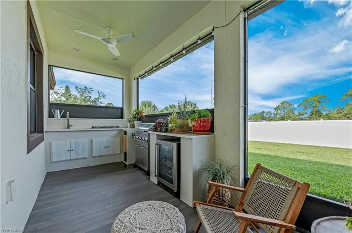 Sunroom / solarium featuring a ceiling fan, beverage cooler, and a sink
