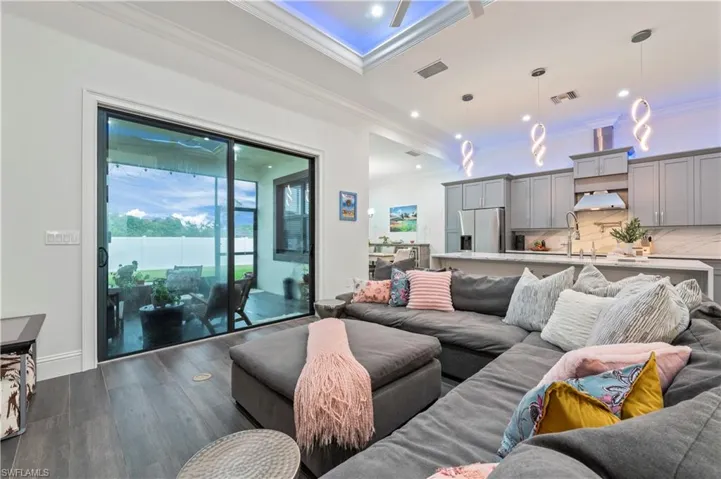 Living area featuring dark wood finished floors, visible vents, recessed lighting, and ornamental molding