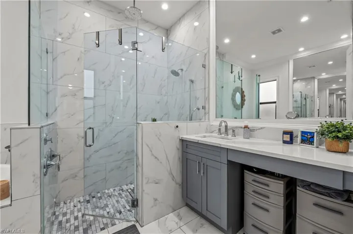 Bathroom with vanity, a marble finish shower, recessed lighting, tile walls, and marble finish floor