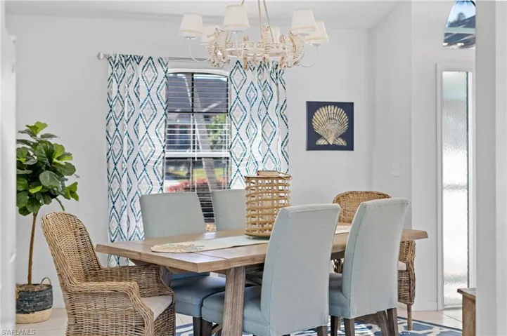 Dining room with tile patterned flooring, a healthy amount of sunlight, and an inviting chandelier