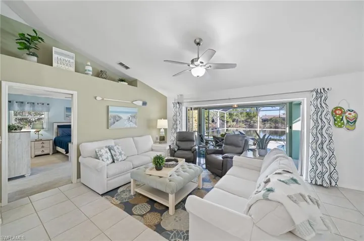 Tiled living room featuring ceiling fan and lofted ceiling