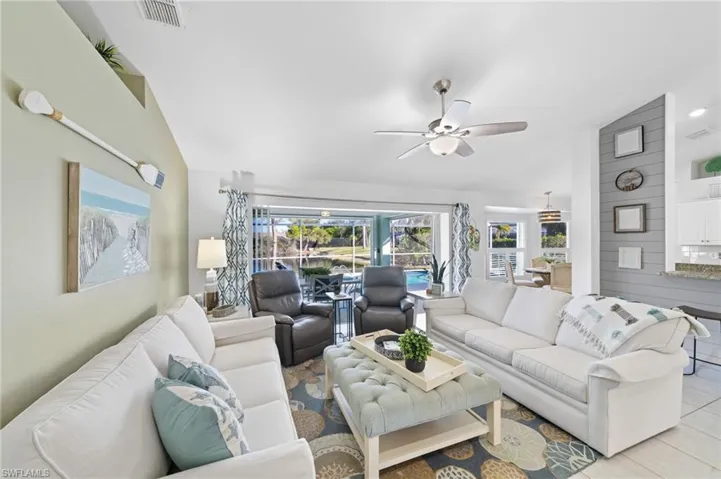 Living room featuring ceiling fan, lofted ceiling, and light tile patterned floors