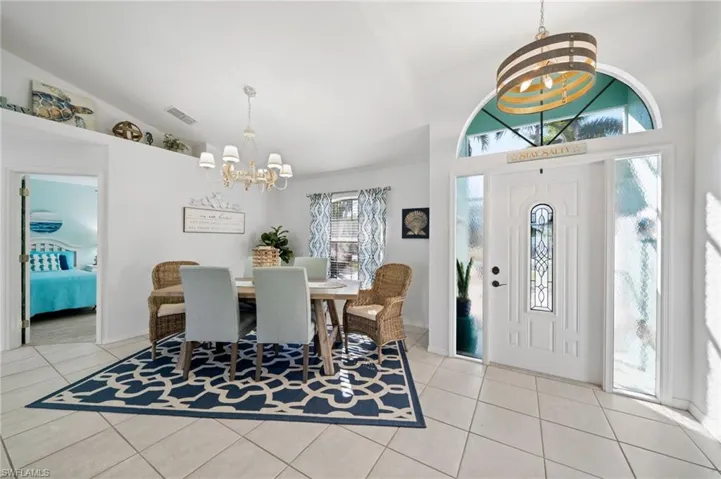 Dining space with light tile patterned flooring, vaulted ceiling, and an inviting chandelier