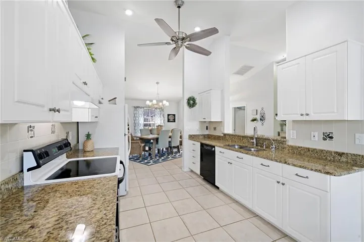 Kitchen featuring white cabinets, ceiling fan with notable chandelier, dark stone countertops, dishwasher, and range