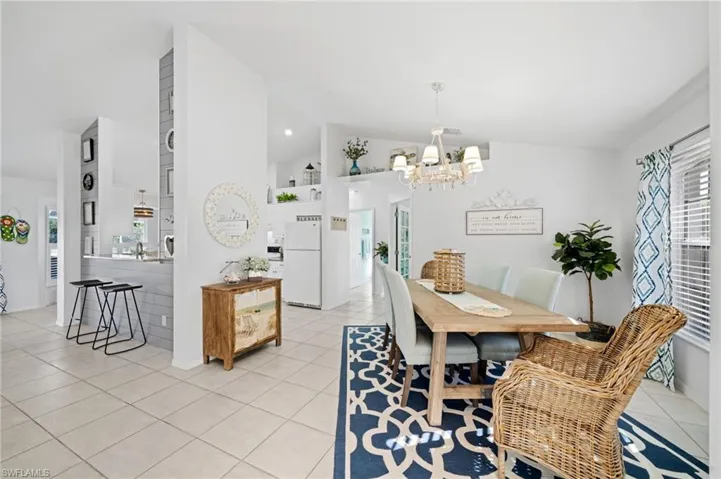 Dining area with an inviting chandelier, light tile patterned floors, and vaulted ceiling