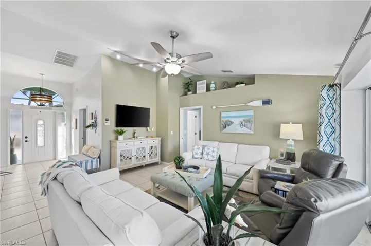 Tiled living room with ceiling fan and high vaulted ceiling