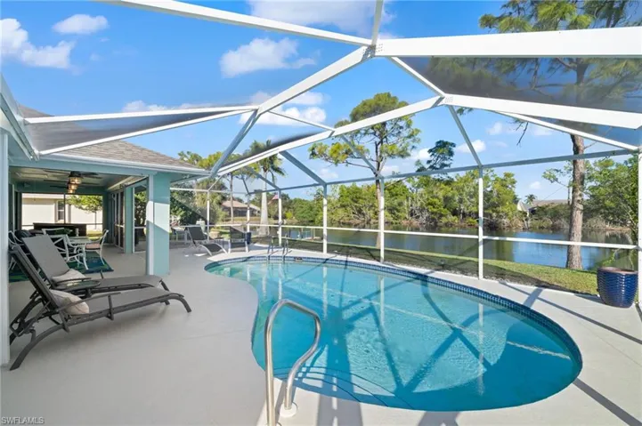 View of swimming pool with a water view, glass enclosure, and a patio area