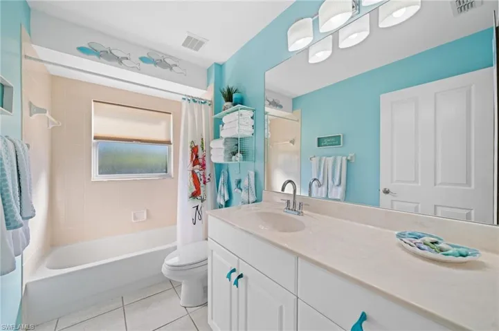 Full bathroom featuring shower / bathtub combination with curtain, tile patterned flooring, vanity, and toilet