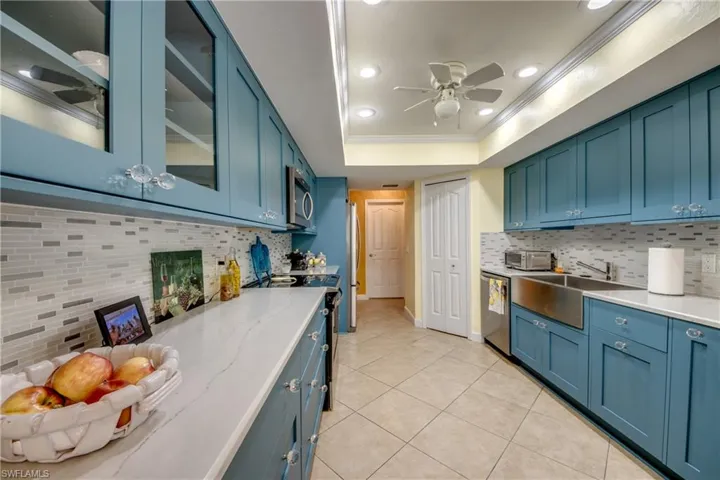 Kitchen with backsplash, sink, blue cabinetry, and stainless steel appliances