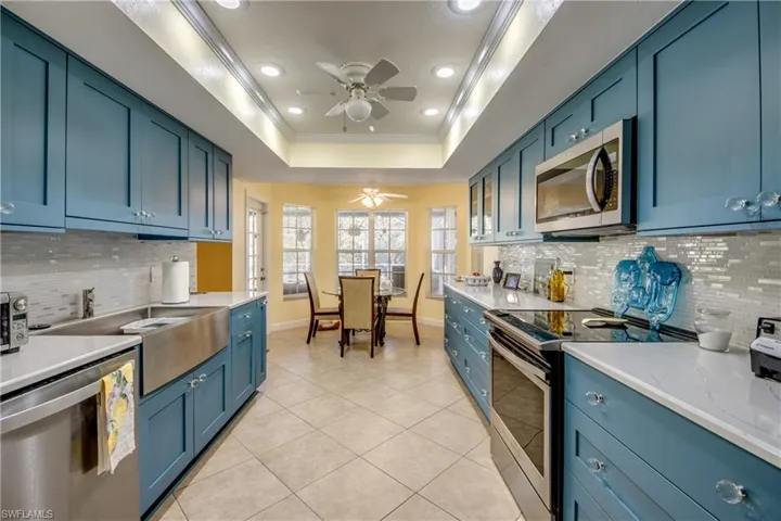 Kitchen with backsplash, light tile patterned floors, ornamental molding, and appliances with stainless steel finishes